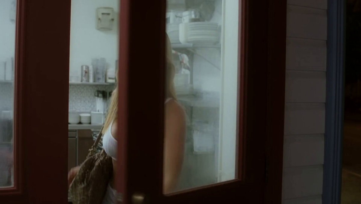 A blonde woman beside a doorway